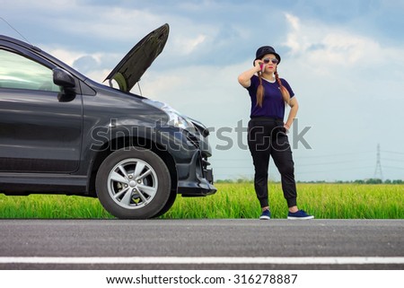 Unfortunate Asian female driver making a phone call after her car breaking down at roadside in rural of Thailand