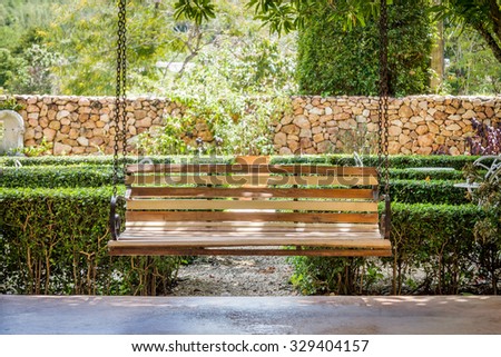 Vintage wooden hanging seat on an airy porch. It brings a feeling of well-being and relaxation.