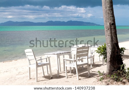 White table set on sand beach facing the ocean