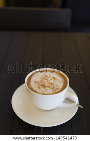 coffee cup on wooden board with yellow wall as background
