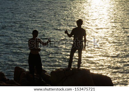 Men silhouette in victory action over sea sunset