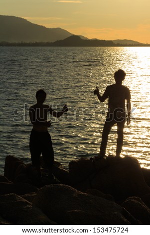 Men silhouette in victory action over sea sunset