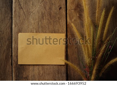 Still life flower foxtail weed and paper pad in golden light on wooden background