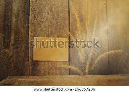 Still life flower foxtail weed and paper pad in morning light on wooden background