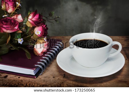 Still life cup of coffee,roses and notebook on wooden table