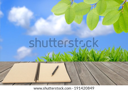 Ecology concept,memo notebook and fresh green field with blue sky in summer