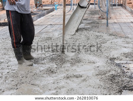 Construction workers spreading freshly poured concrete mix for house building