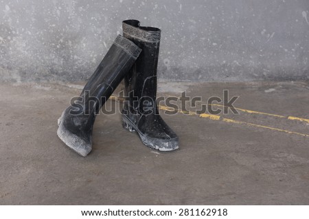 A pair of black gum boots on grunge floor
