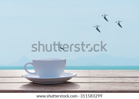 Morning coffee cup with beautiful seascape and white birds background