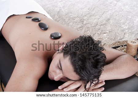 Stone therapy. Man getting a hot stone massage at spa salon