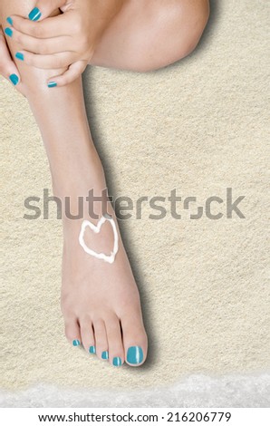 body part shot of beautiful healthy young woman\'s legs. valentines heart is drawn with white care cream on foot