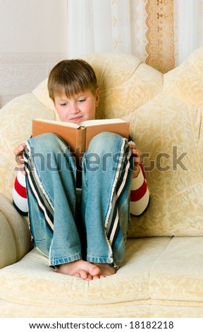 boy reads  book on  sofa