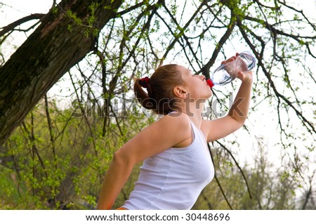 sportswoman drinks water in park