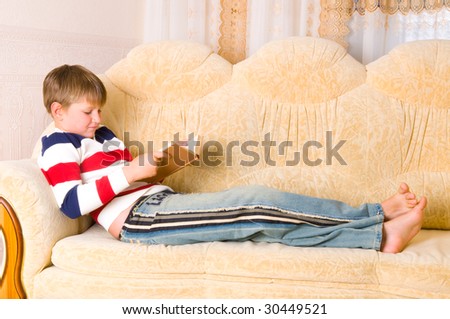 boy reads book on sofa