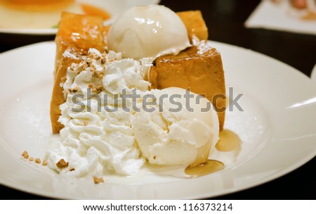 toast with ice cream ,whipping cream and honey syrup on white plate
