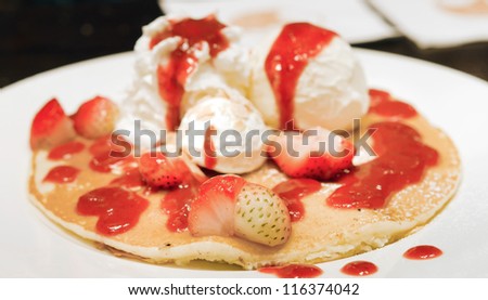pancakes  with  ice cream , whipping cream , fresh strawberries and syrup .