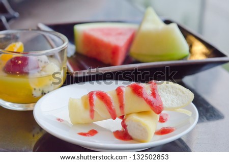 the roll pancakes with the strawberries syrup and cream , fruits on dish  and mix fruits in glass