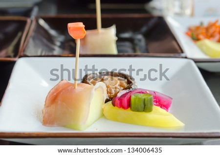 close up fish  and fruit sticks with  melon and mixed pickled vegetable on white dish