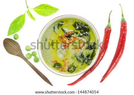 top view green chicken curry in bowl , green vegetable,   red chili  and wooden spoon  over white