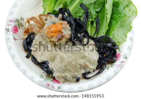 top view black tagliatelle (pasta made with cuttlefish ink) with carbonara sauce  , fried crab and fresh vegetable on white background