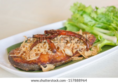 Fried pickled fish , onion  and chili served  with fresh vegetable on dish