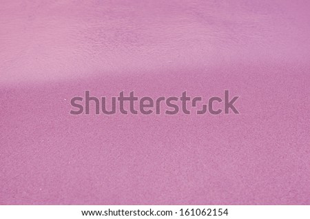 Pink Sandy beach background. Detailed sand texture and water . Top view