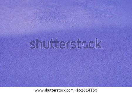 purple  Sandy beach background. Detailed sand texture and water . Top view