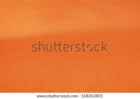 orange  sandy beach background. Detailed sand texture and water .