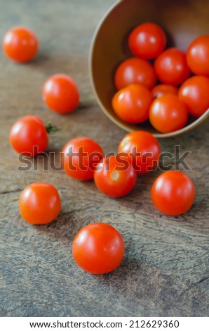 Red cherry tomatoes  spilling out from brown bowl