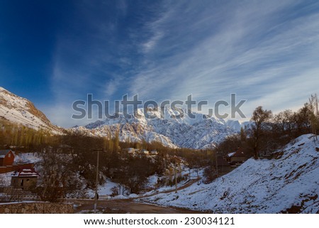 Mountain alps partially covered by snow above small village, late fall