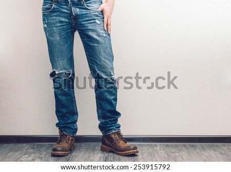 Young fashion man\'s legs in jeans and boots on wooden floor