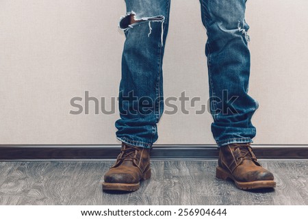 Young fashion man\'s legs in jeans and boots on wooden floor