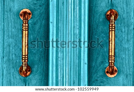Door handles with an old double wood door painted with blue