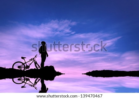 Man and bike silhouette with the sky as background.