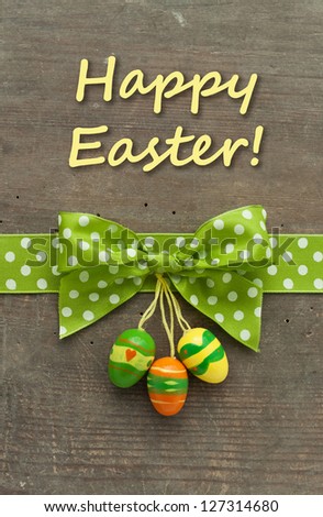 Card with dotted green loop and easter eggs on wooden ground/easter/card