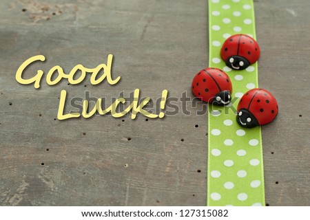 Card with dotted green tape and lady bugs on wooden ground/good luck/lady bugs