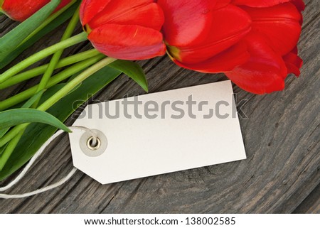 red tulips and label on wooden ground/tulips/flowers