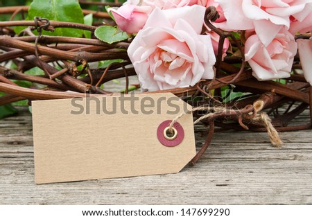 pink roses with label on wooden ground/roses/flowers