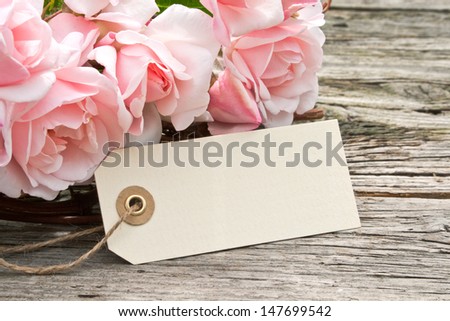 pink roses with label on wooden ground/roses/flowers