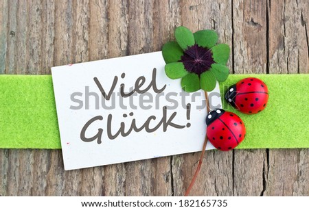 Leafed clover, ladybugs and card on wooden board/good luck/german