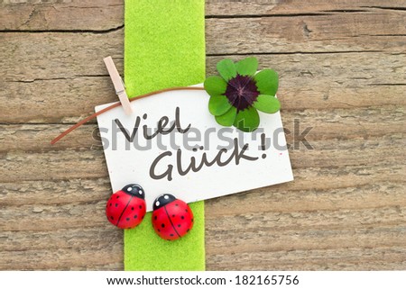Leafed clover, ladybugs and card on wooden board/good luck/german