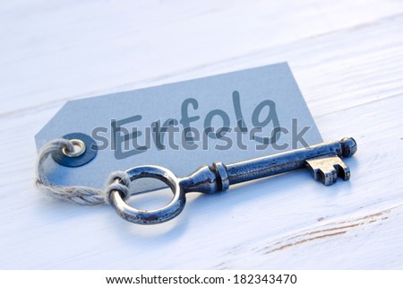 Old key and label with lettering \'Erfolg\' (success in German).