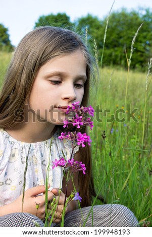 Young girl smelling a flower/nature/meadow