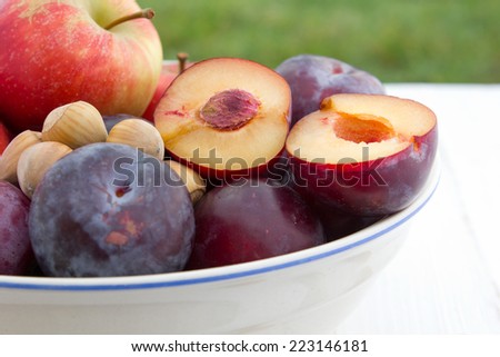 Plums, apples and hazelnuts on white table/fruits/plums