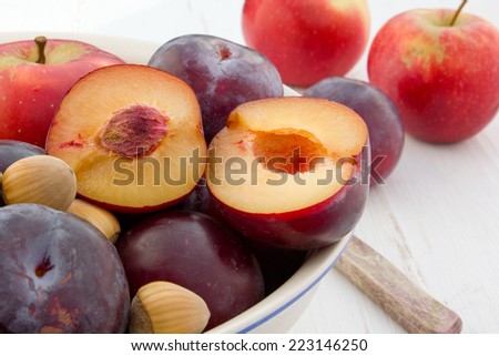 Plums, apples and hazelnuts on white table/fruits/plums