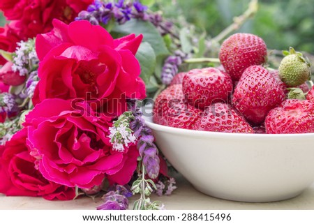 A white bowl with fresh strawberries, roses and herbs / strawberries and roses / strawberry season