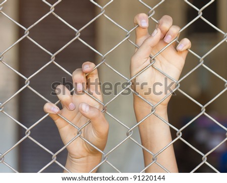 two hands of a man are grabbing mesh cage