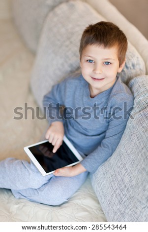 Little boy with iPad sitting on the sofa