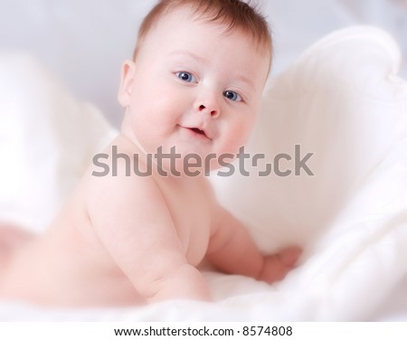 beautiful smiling baby boy in the white bed-sheet