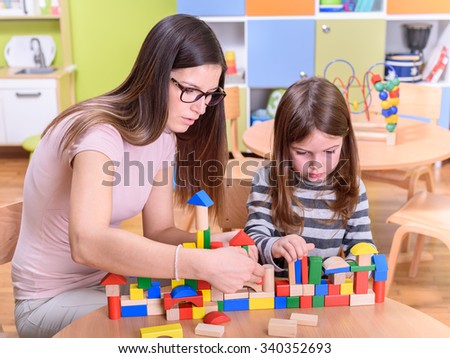 Kindergarten Teacher and Kid Concentrated on Play